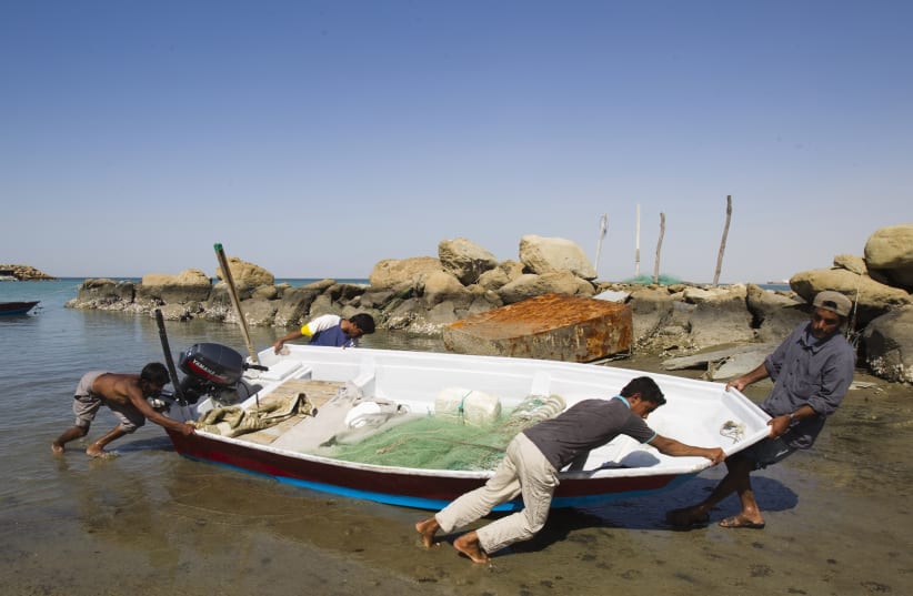 Local Baluch fishermen push a boat to the shore at a fishing port in Tiss village in the suburb of the port city of Chabahar 1,452 km (902 miles) southeast of Tehran, near Strait of Hormuz January 16, 2012. (photo credit: REUTERS/RAHEB HOMAVANDI)
