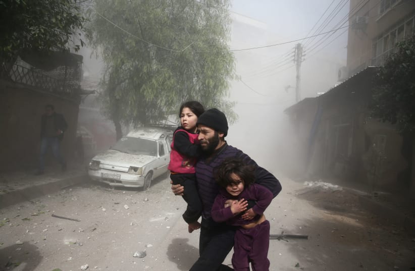 A man runs amid dust after an airstrike in the besieged town of Douma in eastern Ghouta in Damascus, Syria (photo credit: REUTERS/BASSAM KHABIEH)