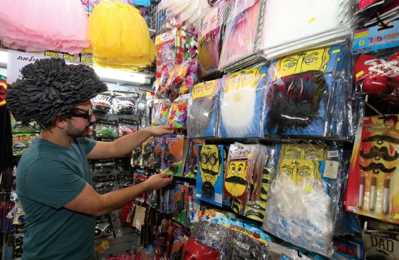 A CUSTOMER tries on a disguise and looks at costumes in a Jerusalem shop this week. (Marc Israel Sellem/The Jerusalem Post) (photo credit: MARC ISRAEL SELLEM/THE JERUSALEM POST)