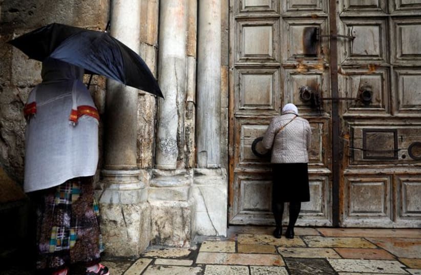 Worshippers stand in front of the closed doors of the Church of the Holy Sepulchre in Jerusalem's Old City February 26, 2018. REUTERS/Ronen Zvulun (photo credit: REUTERS/Ronen Zvulun)