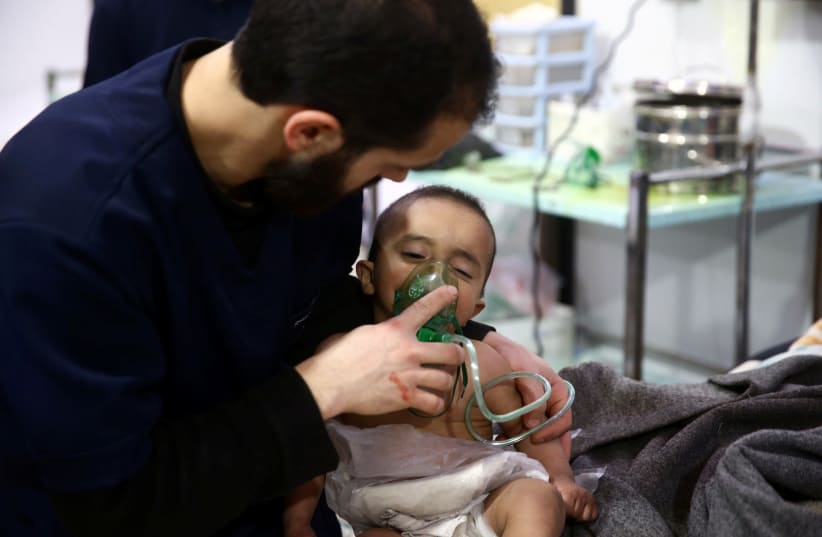 Man with a child in a hospital in the besieged town of Douma, Eastern Ghouta, Damascus, Syria (photo credit: REUTERS/BASSAM KHABIEH)