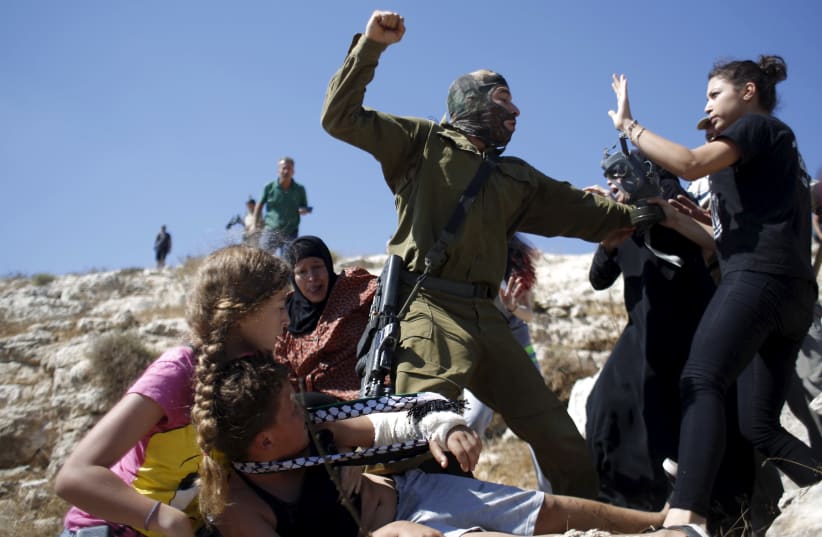 The Tamimi family scuffles with an Israeli soldier as they try to prevent him from detaining a boy during a protest against Jewish settlements in the West Bank village of Nabi Saleh, August 28, 2015 (photo credit: MOHAMAD TOROKMAN/REUTERS)