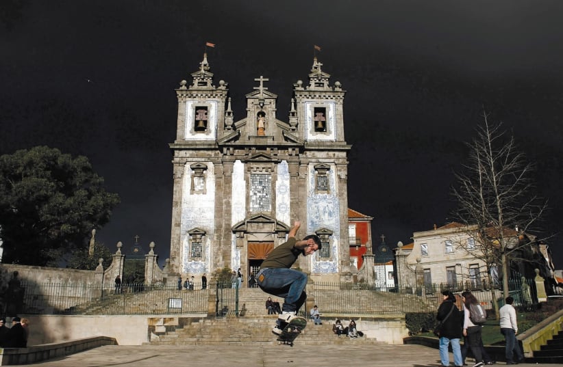 A boy performs with his skateboard in front of Santo Ildefonso Church at Batalha Square in Porto, northern Portugal (photo credit: REUTERS)