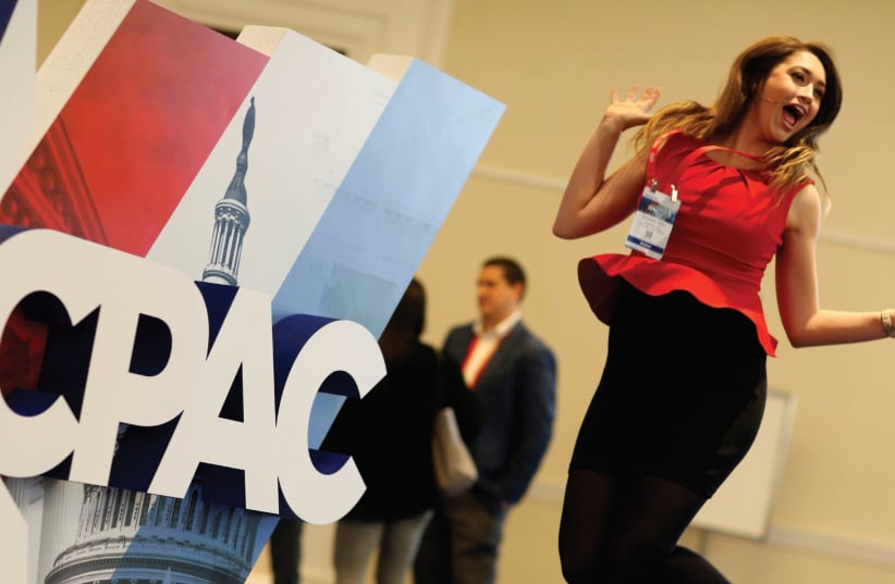 A WOMAN jumps in front of the Conservative Political Action Conference (CPAC) sign at National Harbor, Maryland, last month. (photo credit: REUTERS)