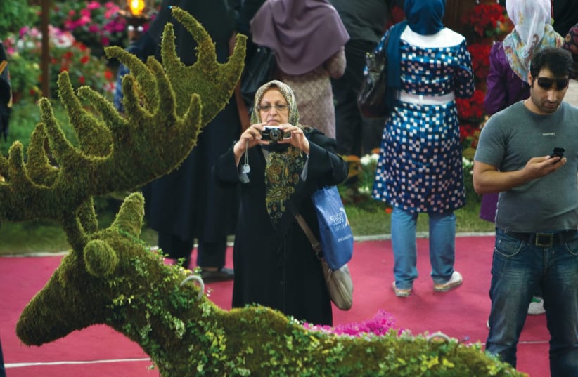 AN IRANIAN WOMAN photographs a shrub trimmed like a deer. Not so long ago, deer played a key role in Israel-Iran relations. (Reuters) (photo credit: REUTERS)