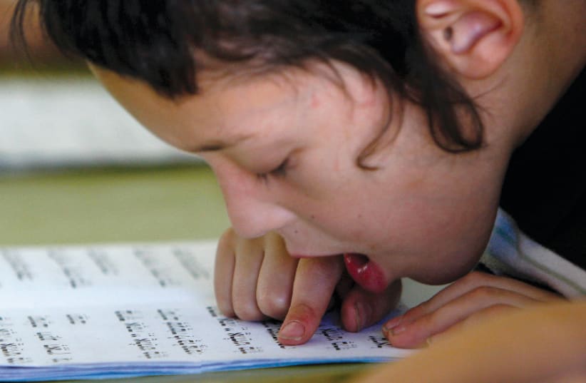 A HAREDI child reads from the Bible during a reading class at the Kehilot Ya’acov Torah School for boys in Jerusalem in 2010 (photo credit: RONEN ZVULUN / REUTERS)