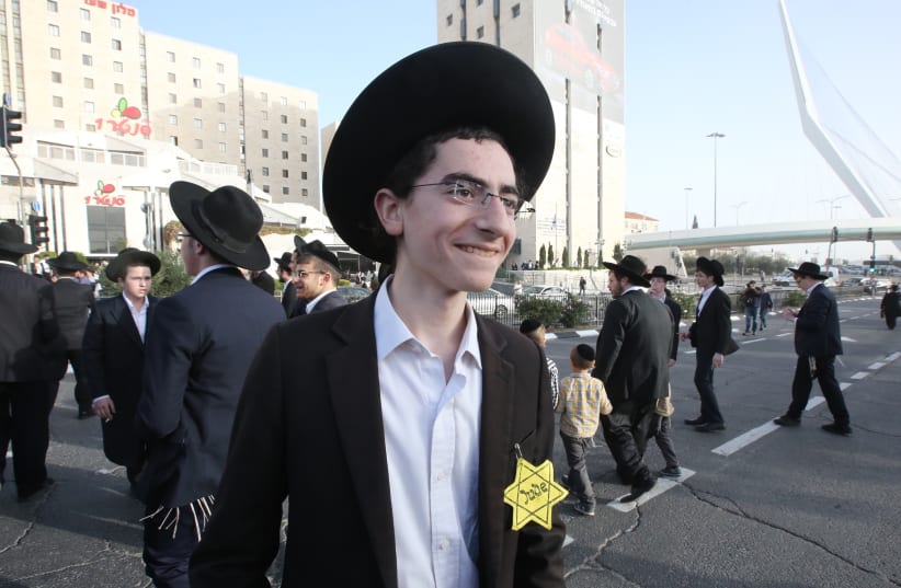 A young haredi boy wearing a "Jude" star takes part in a protest against mandatory IDF conscription, March 2018 (photo credit: MARC ISRAEL SELLEM/THE JERUSALEM POST)