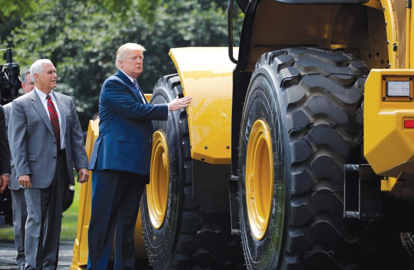 US PRESIDENT Donald Trump and Vice President Mike Pence stand next to Caterpillar equipment as they visit a ‘Made in America’ products showcase at the White House in July. (photo credit: CARLOS BARRIA / REUTERS)