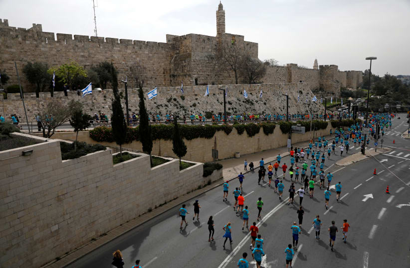Athletes run outside Jerusalem's Old City during the seventh International Jerusalem Marathon March 17, 2017. (photo credit: REUTERS/Ronen Zvulun)