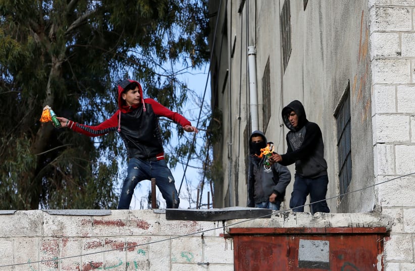 Palestinian demonstrators hurl molotov cocktails at Israeli troops during clashes at a protest against Trump's decision on Jerusalem, in Hebron, in the occupied West Bank March 9, 2018. (photo credit: MUSSA QAWASMA / REUTERS)