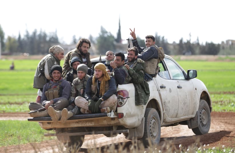Rebel fighters from 'Jaysh al-Sunna' gesture as they ride a vehicle in Tel Mamo village, in the southern countryside of Aleppo, Syria (photo credit: KHALIL ASHAWI / REUTERS)