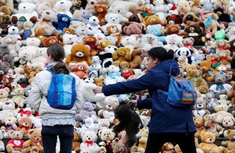 Berlin school pupils set up 740 teddy bears in front at of the concert hall Konzerthaus during an event of the World Vision Organisation to make aware of 740,000 Syrian refugee children who can't attend the school, in Berlin, Germany, March 15, 2018 (photo credit: HANNIBAL HANSCHKE/REUTERS)