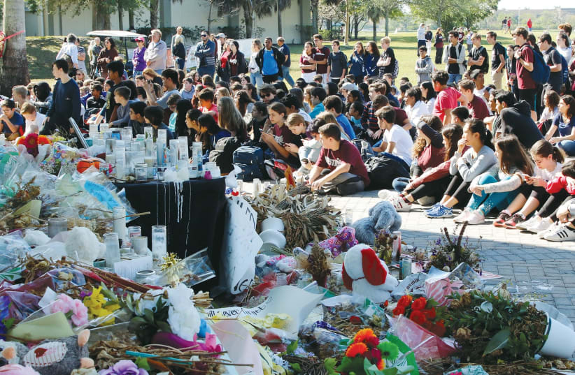 Students from Marjory Stoneman Douglas High School and Westglades Middle School gather near memorials at a park where they marched as part of a National School Walkout, to honor the 17 students and staff members killed at the high school in Parkland, Florida (photo credit: REUTERS)