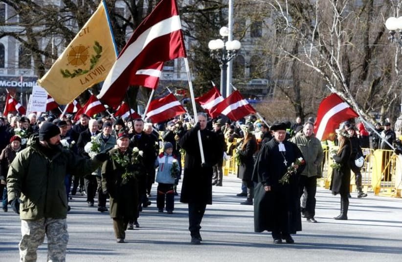 People participate in the annual procession commemorating the Latvian Waffen-SS (Schutzstaffel) unit, also known as the Legionnaires, in Riga, Latvia March 16, 2018 (photo credit: REUTERS/INTS KALNINS)