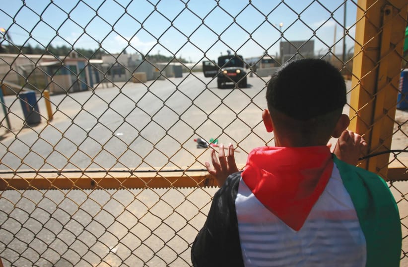 A young Palestinian stands outside Ofer Prison near Ramallah. B’Tselem finds fault with the way IDF West Bank courts treat minors who have been arrested (photo credit: FADI AROURI/REUTERS)