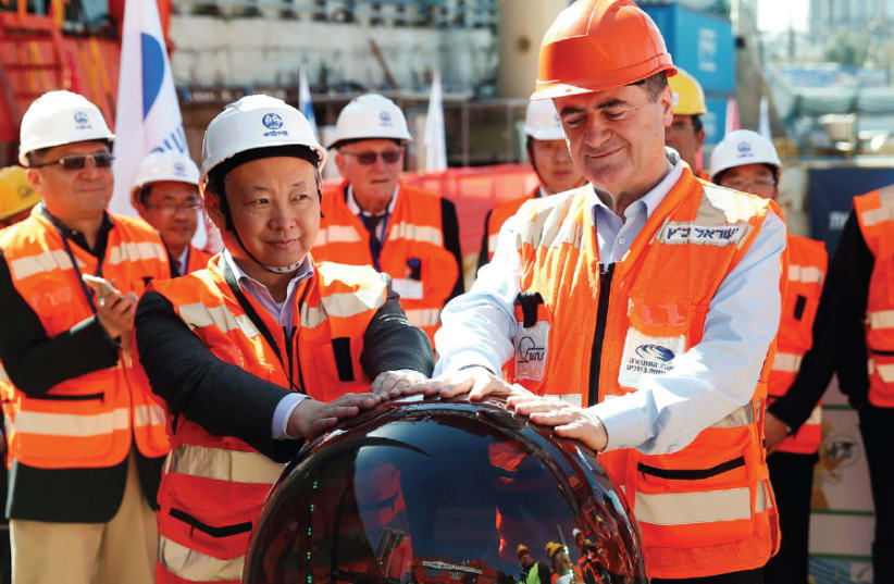 Transportation Minister Israel Katz and employees of China Railway Engineering Corporation join hands in an event marking the beginning of underground construction work of the light rail in Tel Aviv, 2018 (photo credit: BAZ RATNER/REUTERS)