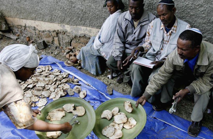 An Ethiopian Jewish woman gives matzahto a man ahead of Passover at a compound while awaiting immigration to Israel in Gondar March 9, 2007  (photo credit: ELIANA APONTE/REUTERS)