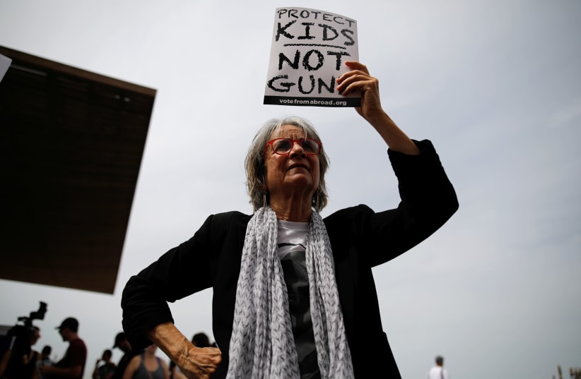 A woman takes part in a protest in front of the US Embassy, calling for enhanced gun control in the US, in Tel Aviv, Israel, March 23, 2018. (photo credit: REUTERS/CORINNA KERN)