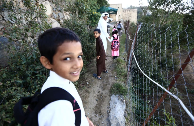 Saudi man Yazid al-Fefi walks with his children as they make their way to their schools through Fifa Mountain, in Jazan, south of Saudi Arabia, December 15, 2016. Picture take December 15, 2016.   (photo credit: MOHAMED AL HWAITY/REUTERS)