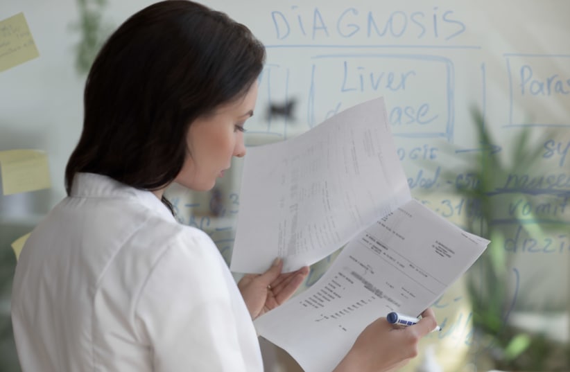 A doctor examines patient medical records. [Illustrative] (photo credit: INGIMAGE)