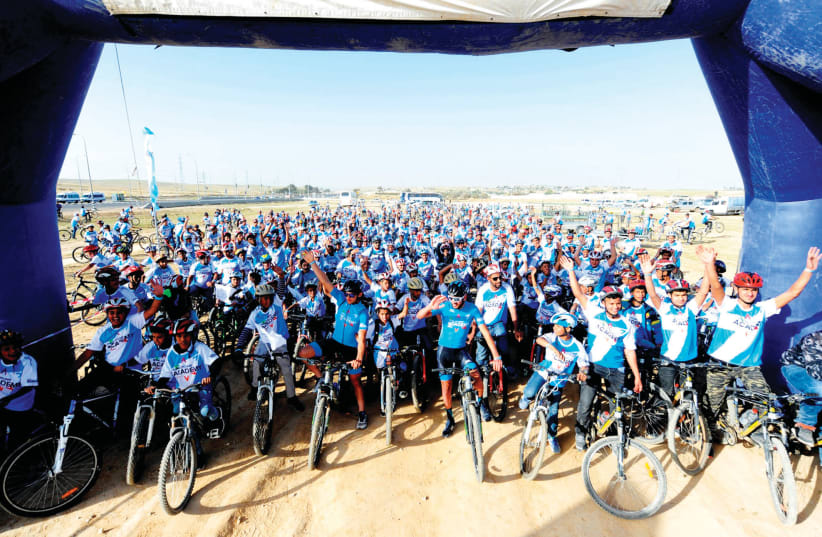 Over 500 children from the Beduin village of Wadi al-Na’am were treated to an event arranged by the Israel Cycling Academy, receiving bikes and racing shirts while taking part in a five-kilometer course with riders from ICA ’s development team. (photo credit: VELOIMAGES/COURTESY)