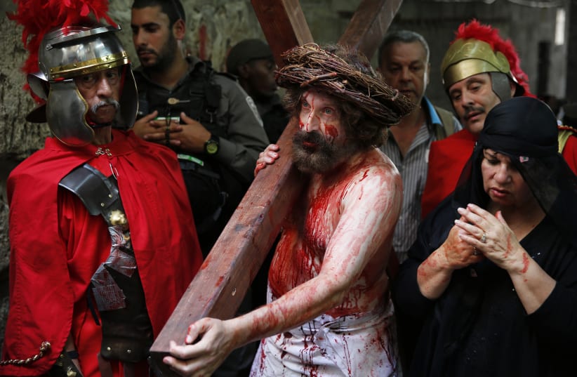 A man playing the role of Jesus carries a cross during a procession along the Via Dolorosa on Good Friday during Holy Week, in Jerusalem's Old City April 18, 2014. (photo credit: FINBARR O'REILLY / REUTERS)