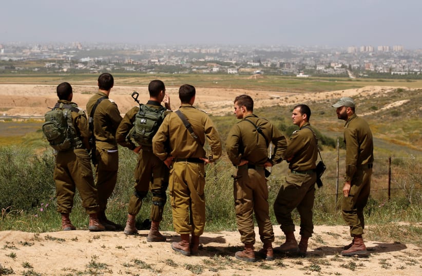 Israeli soldiers listen to a briefing on the Israeli side of the border with the northern Gaza Strip, Israel, March 29, 2018. (photo credit: REUTERS/AMIR COHEN)