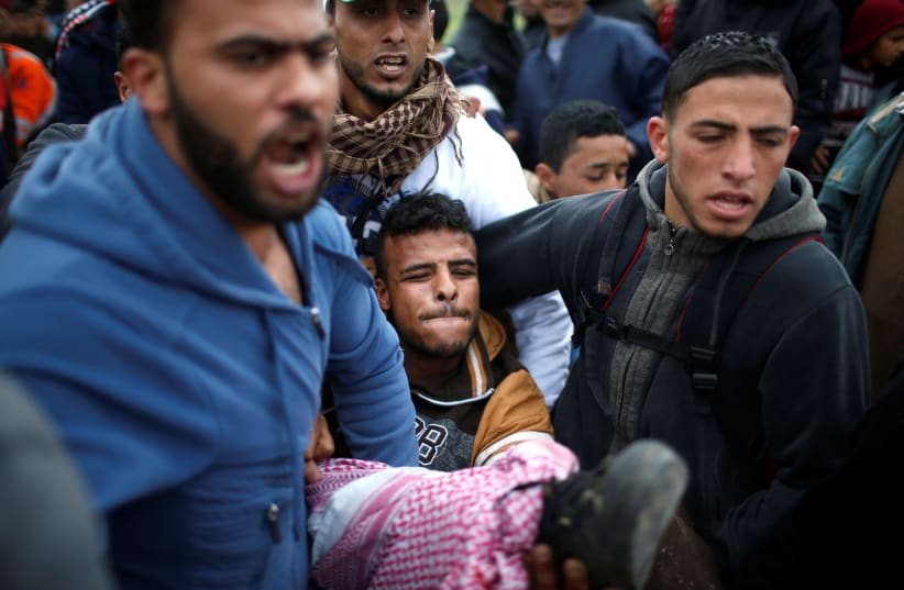 A wounded Palestinian is evacuated during clashes during a protest along the Israel border with Gaza, east of Gaza City March 30, 2018.  (photo credit: REUTERS/MOHAMMED SALEM)