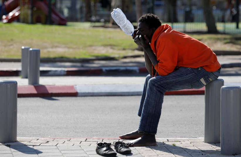 An African migrant sits on the street in Tel Aviv, Israel January 31, 2018. (photo credit: REUTERS/AMIR COHEN)