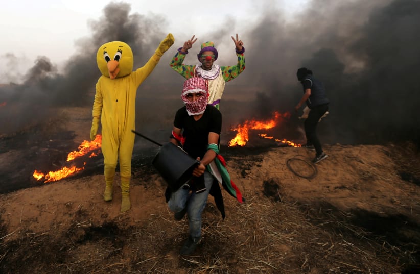Palestinians wearing costumes are seen at the clashes scene at Israel-Gaza border in the southern Gaza Strip April 5, 2018. (photo credit: IBRAHEEM ABU MUSTAFA / REUTERS)