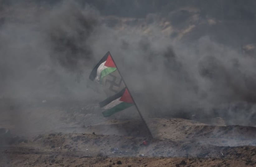 Palestinian flags flank a swastika in the midst of smoke during protests in Gaza (photo credit: IDF SPOKESMAN’S UNIT)
