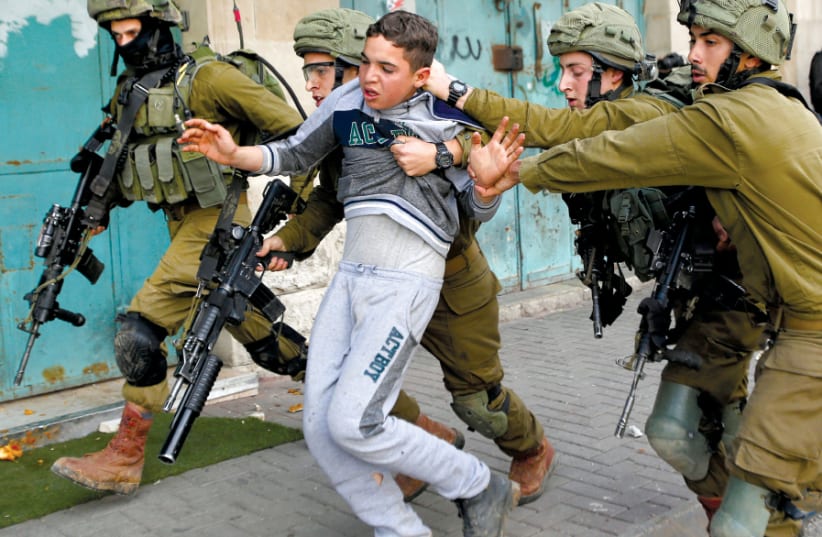 IDF SOLDIERS detain a Palestinian during clashes at a protest in Hebron in February (photo credit: REUTERS/MUSSA QAWASMA)