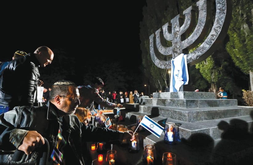 People place candles in 2016 and fly Israeli flags during a ceremony commemorating the victims of Babi Yar, one of the biggest single massacres of Jews during the Holocaust, next to Kiev (photo credit: REUTERS)