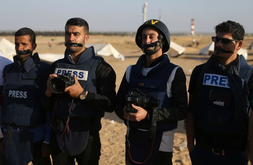 Journalists take part in a protest against the killing of Palestinian journalist Yasser Murtaja, at the Israel-Gaza border, in the southern Gaza Strip April 8, 2018. (photo credit: REUTERS/IBRAHEEM ABU MUSTAFA)