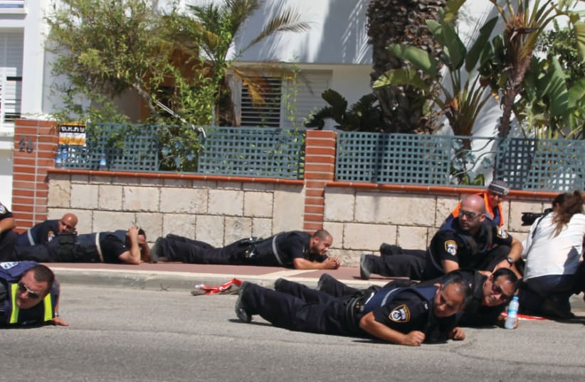 Police officers duck for cover in Sderot as a siren wails in the background during Operation Protective Edge (photo credit: TOVAH LAZAROFF)