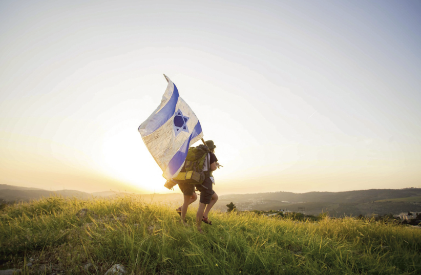 Two hikers carry an Israeli flag near Castel as part of the Masa 70 trek  (photo credit: TOMER BEN-AVI)