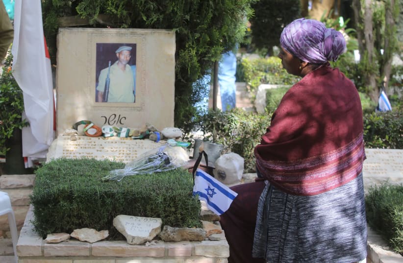 An Israeli visits the grave of a fallen soldier on Mount Herzl during Remembrance Day on April 18th, 2018. (photo credit: MARC ISRAEL SELLEM/THE JERUSALEM POST)