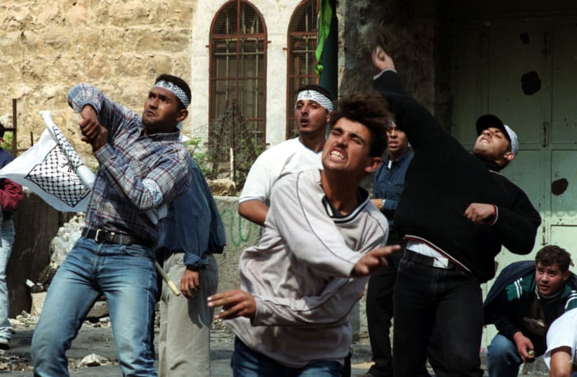 Palestinians hurl rocks at Israeli security forces during clashes in the West Bank town of Hebron October 16, 2000. (photo credit: REUTERS)