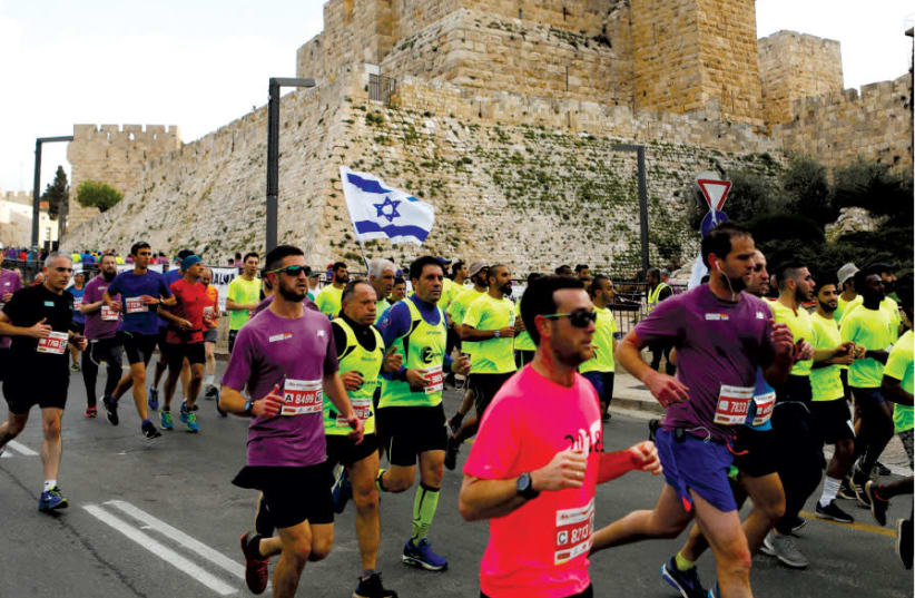 ATHLETES RUN outside the Old City during the eighth International Jerusalem Marathon, April 2018 (photo credit: RONEN ZVULUN / REUTERS)
