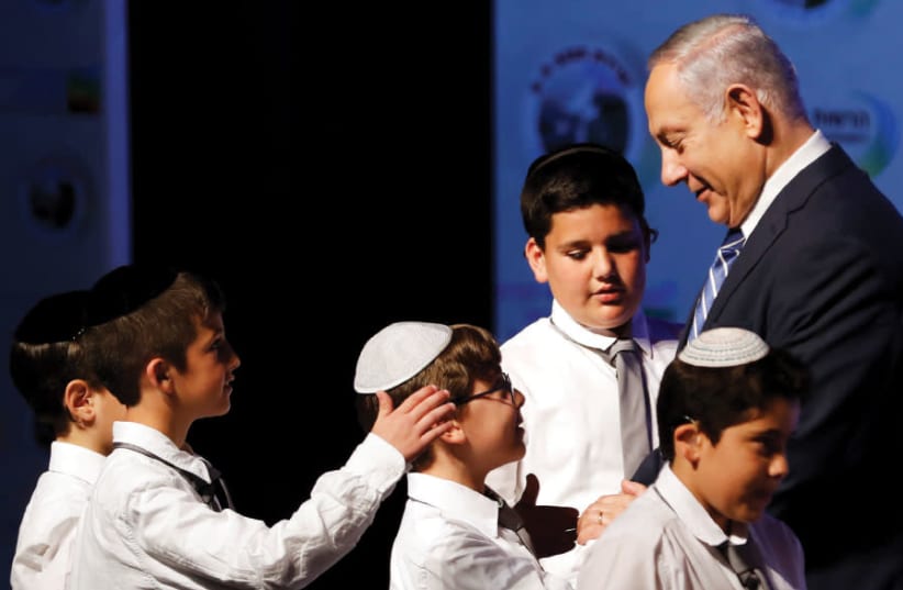 PRIME MINISTER Benjamin Netanyahu shakes hands with children during a regional development conference in Dimona, March 2018 (photo credit: RONEN ZVULUN / REUTERS)