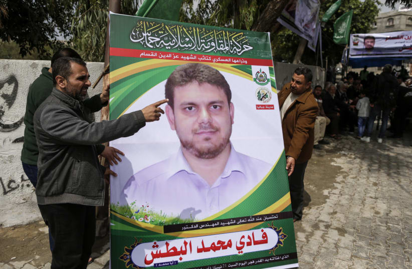 Men holding up a poster portrait of 35-year-old Palestinian professor and Hamas member Fadi Mohammad al-Batsh, who was killed in Malaysia, outside his family's house in Jabalia in the northern Gaza Strip.  (photo credit: MAHMUD HAMS / AFP)