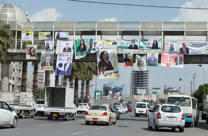 Vehicles drive under campaign posters ahead of the parliamentary election, in Erbil, Iraq (photo credit: AZAD LASHKARI / REUTERS)
