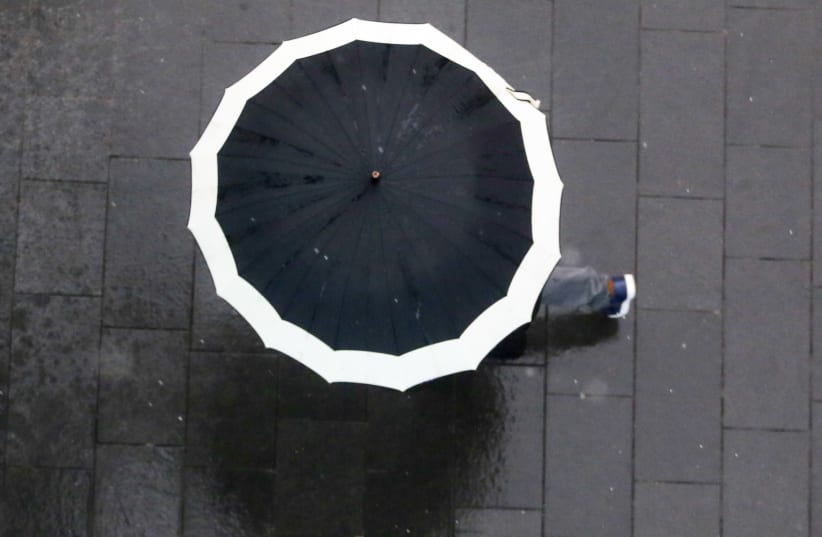 A person walks with an umbrella during a rain storm in Jerusalem, April 25, 2018 (photo credit: MARC ISRAEL SELLEM/THE JERUSALEM POST)
