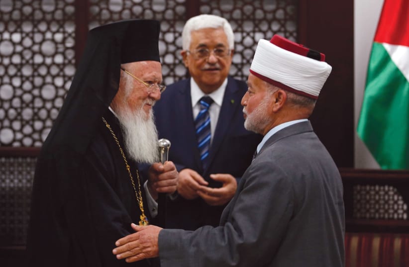 Grand Mufti of Jerusalem Muhammad Ahmad Hussein (R) shakes hands with Ecumenical Orthodox Patriarch Bartholomew I of Constantinople during a meeting with Palestinian President Mahmoud Abbas (C) in the West Bank city of Ramallah in 2014 (photo credit: REUTERS)