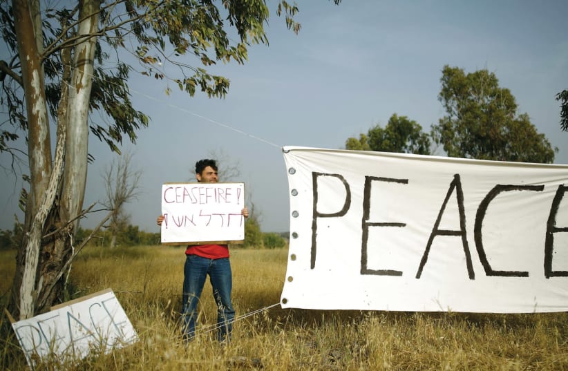 A PEACE activist holds up a sign near Gaza. (photo credit: REUTERS)