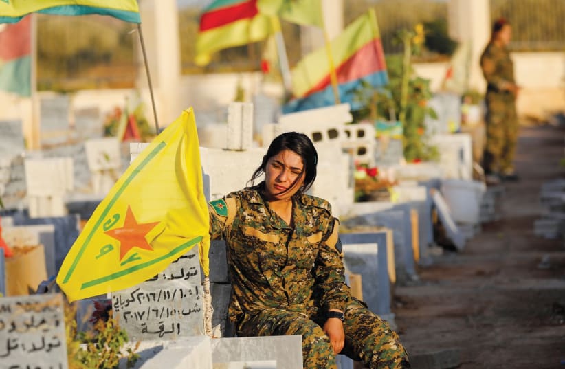 A MEMBER of the Syrian Democratic Forces mourns at the grave of a fallen comrade. (photo credit: REUTERS)