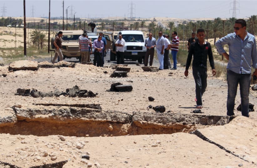 EGYPTIAN SECURITY officials inspect the site of a bomb blast targeted at soldiers on the highway between El-Arish and the border town of Rafah, in the troubled northern part of the Sinai Peninsula, in 2015 (photo credit: REUTERS)