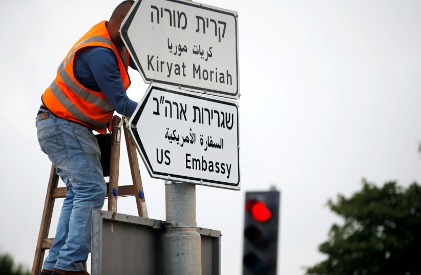 A worker hangs a road sign directing to the US embassy, in the area of the US consulate in Jerusalem, May 7, 2018.  (photo credit: REUTERS/Ronen Zvulun)