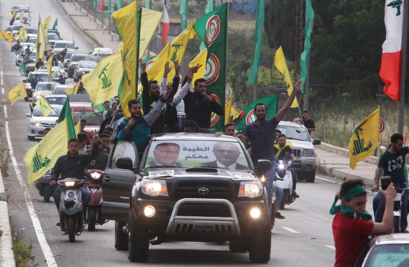 Supporters of Lebanon's Hezbollah and Amal Movement gesture as they ride in a car in Marjayoun, Lebanon May 7, 2018 (photo credit: AZIZ TAHER/REUTERS)
