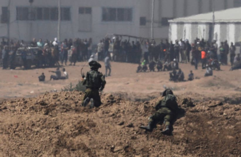 Israeli soldiers, on the Israeli side of the border with the Gaza Strip, watch Palestinian protesters in Gaza May 14, 2018 (photo credit: REUTERS/AMIR COHEN)